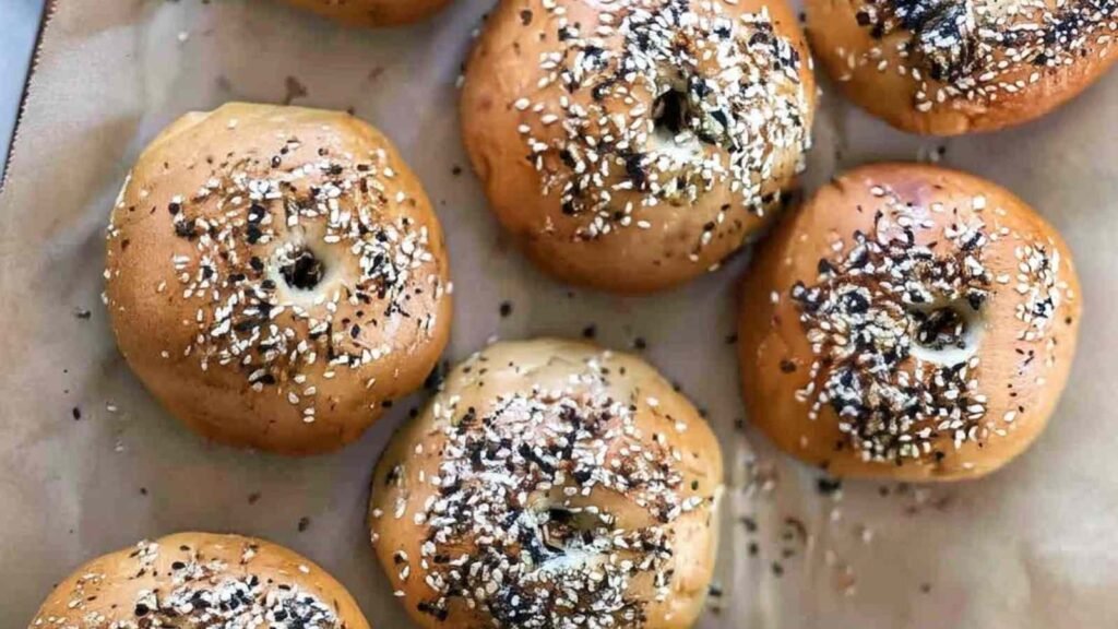 Freshly baked sourdough discard bagels topped with everything seasoning, resting on parchment paper.
