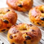 Freshly baked cinnamon raisin bagels cooling on a wire rack, with golden crust and visible raisins