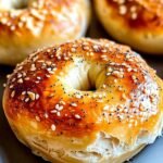 Close-up of a freshly baked Greek yogurt bagel with a shiny golden crust, puffy texture, and topped with sesame and poppy seeds