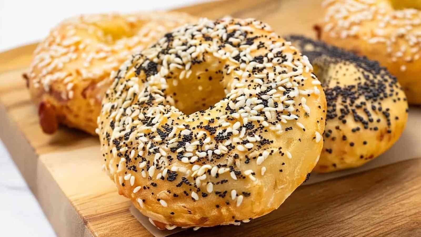 Close-up of golden-baked Cottage Cheese Bagels with Almond Flour, sprinkled with poppy and sesame seeds on a wooden board