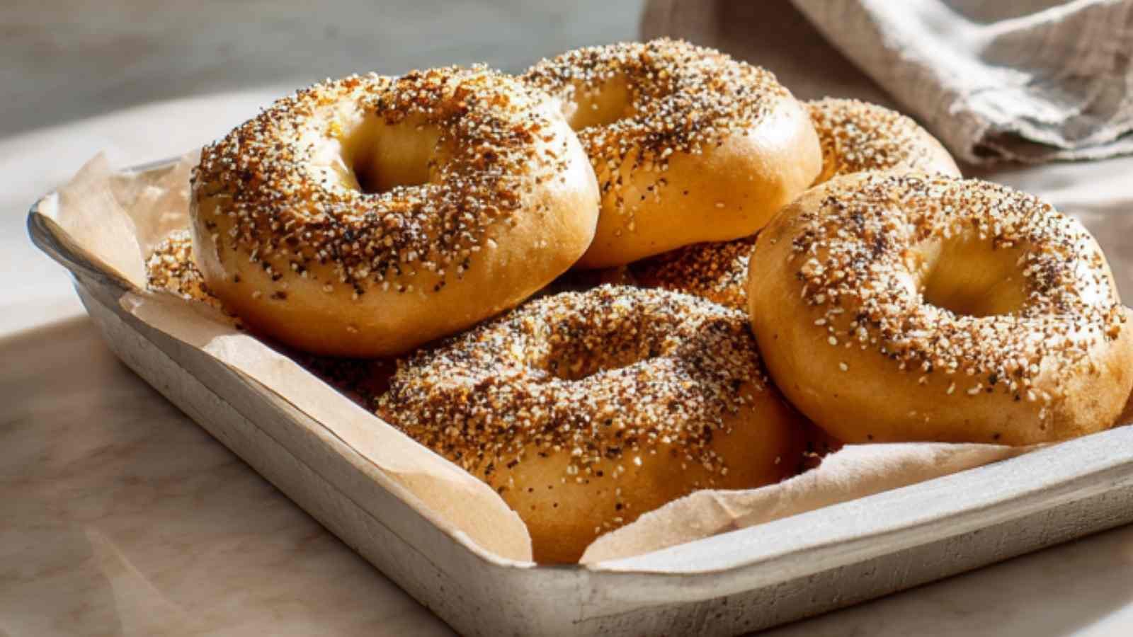 Close-up of freshly baked Greek yogurt bagels topped with everything seasoning in a parchment-lined baking tray