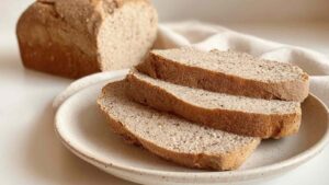 Close-up of sliced flourless bread on a ceramic plate showing its soft, dense interior and golden crust
