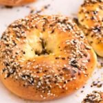Close-up of golden brown cottage cheese bagels topped with everything bagel seasoning on parchment paper