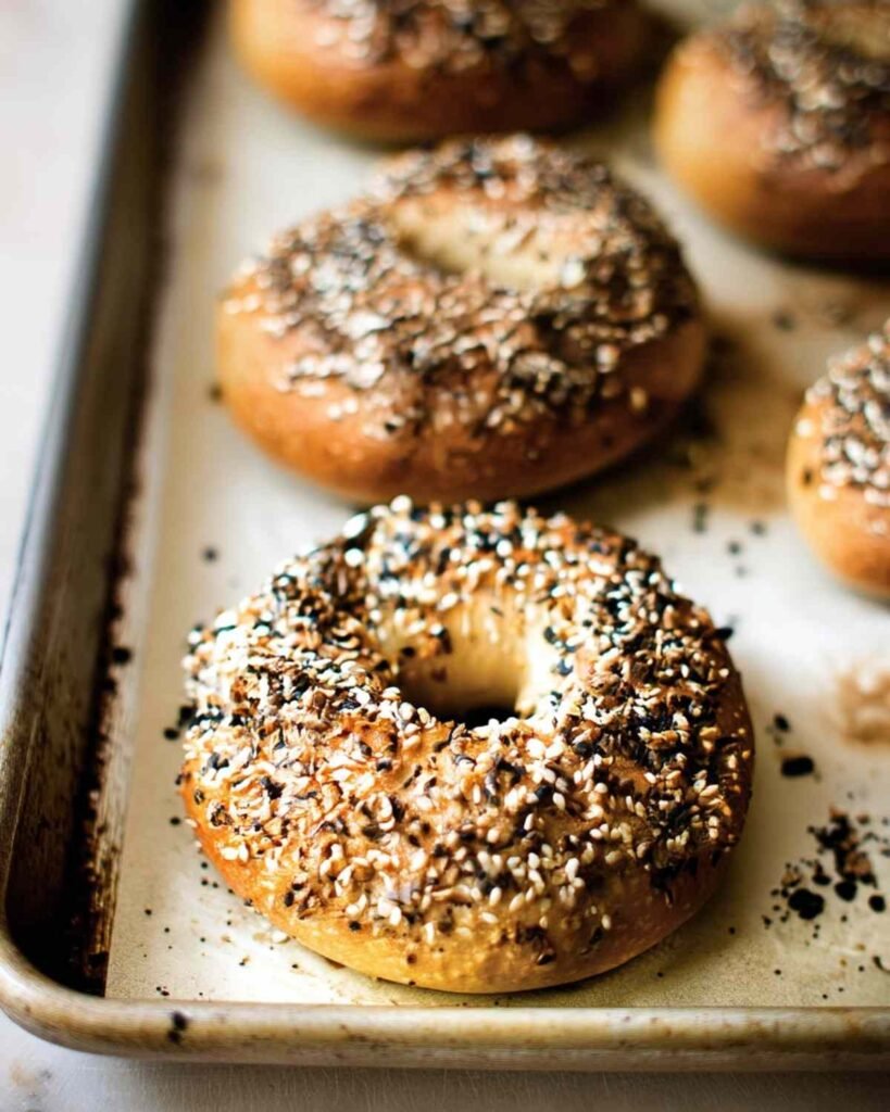 Freshly baked everything bagels with golden crusts on a baking tray lined with parchment