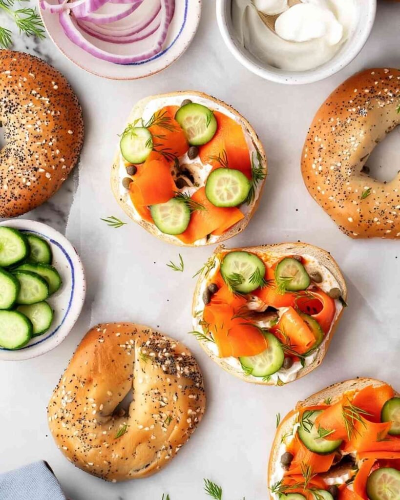 Overhead shot of vegan lox bagels arranged with cucumbers, red onions, dill, and everything bagels.