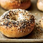 Close-up of golden-brown everything bagels fresh from the oven on a baking tray
