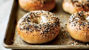 Close-up of golden-brown everything bagels fresh from the oven on a baking tray