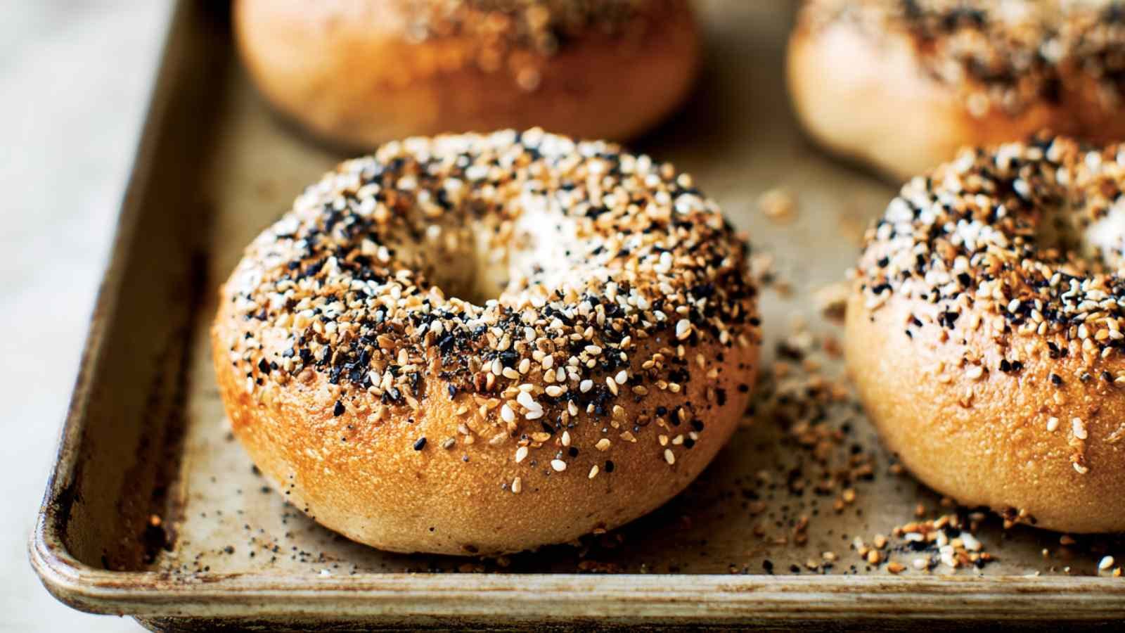 Close-up of golden-brown everything bagels fresh from the oven on a baking tray
