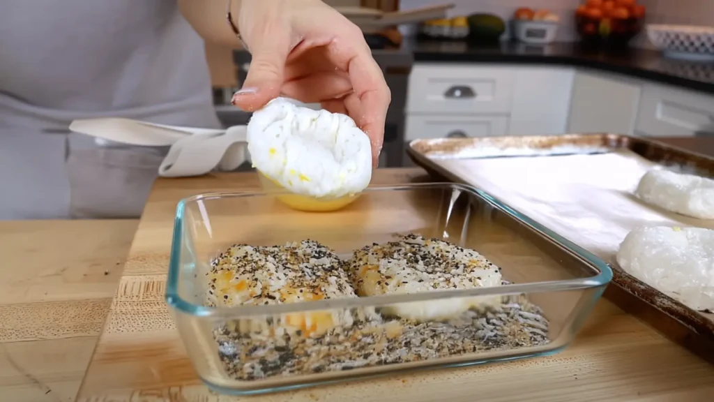 Raw bagel dipped into everything bagel seasoning mix