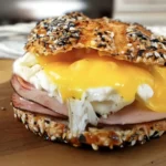 Cottage cheese bagel sandwich filled with egg, ham, and melted cheese