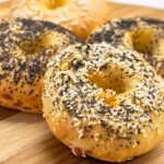 Stack of Cottage Cheese Bagels with Almond Flour on wooden board, topped with sesame and poppy seeds