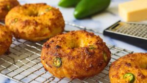 Gluten-free jalapeño cheddar bagels cooling on a wire rack, golden and bubbly with melted cheese and sliced jalapeños visible