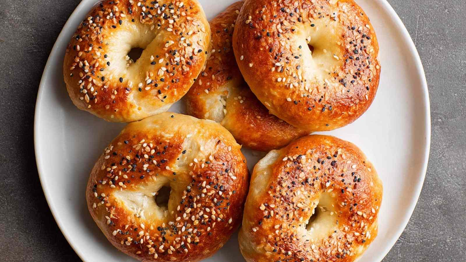 Golden brown air fryer bagels on a white plate, topped with sesame and everything seasoning