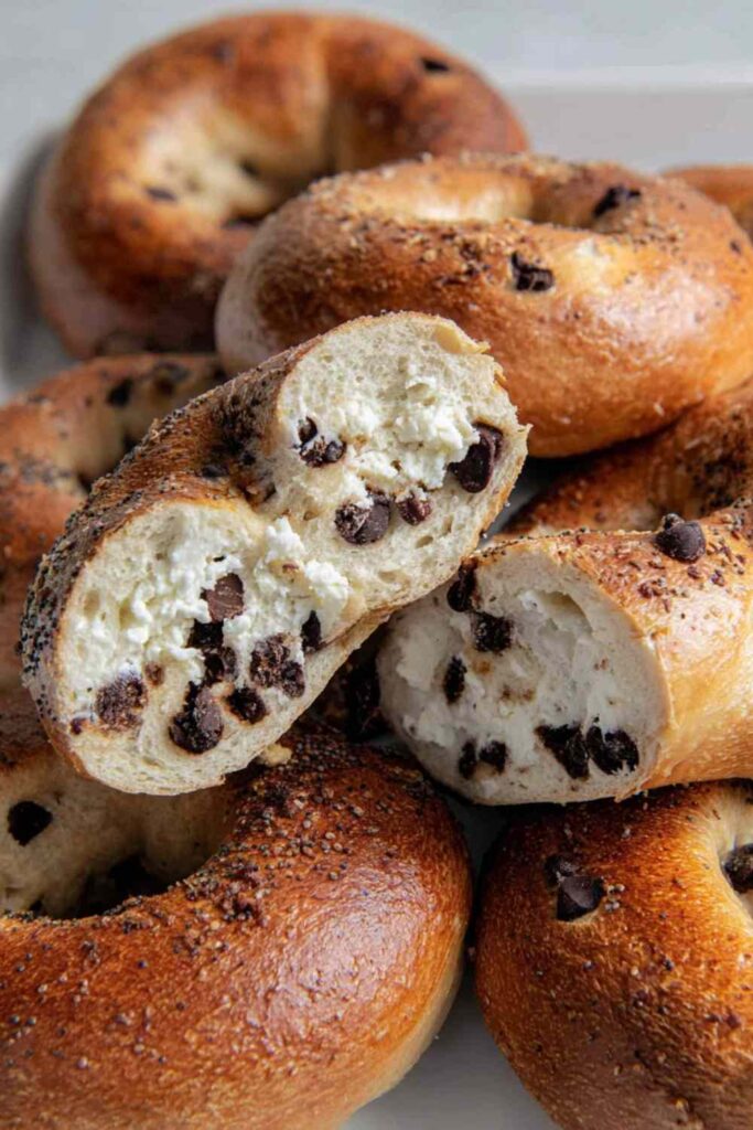 Golden baked chocolate chip bagels, close up with cream cheese filling visible inside.