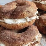 Close-up of stacked cinnamon sugar bagels with cream cheese filling, coated in golden cinnamon sugar.
