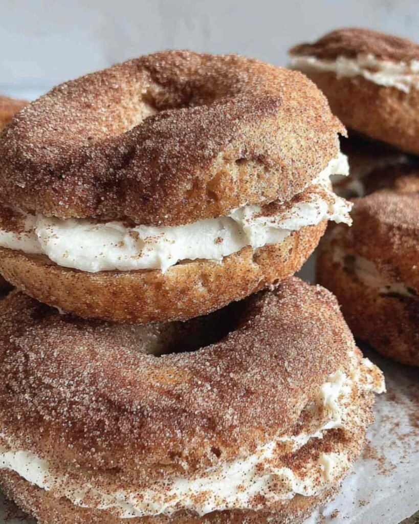 Close-up of stacked cinnamon sugar bagels with cream cheese filling, coated in golden cinnamon sugar.