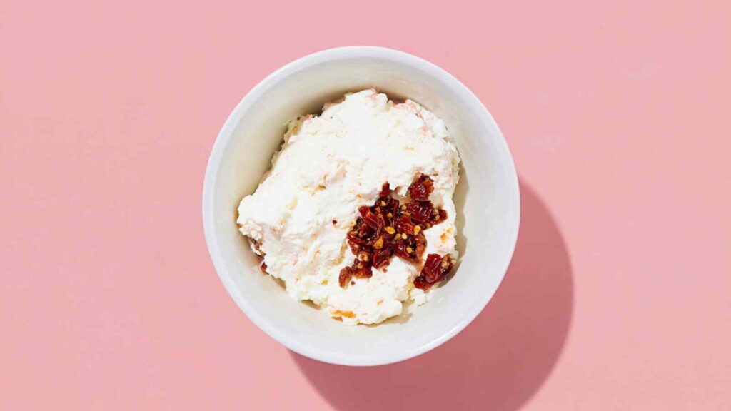 White bowl with whipped cream cheese and chopped chipotle peppers in adobo.