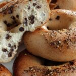 Close-up of chocolate chip bagels, one torn open to reveal soft interior and melted chips.
