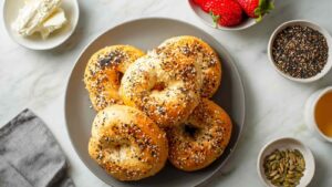 Golden-brown cottage cheese bagels topped with everything seasoning on a gray plate, served with cream cheese and strawberries.