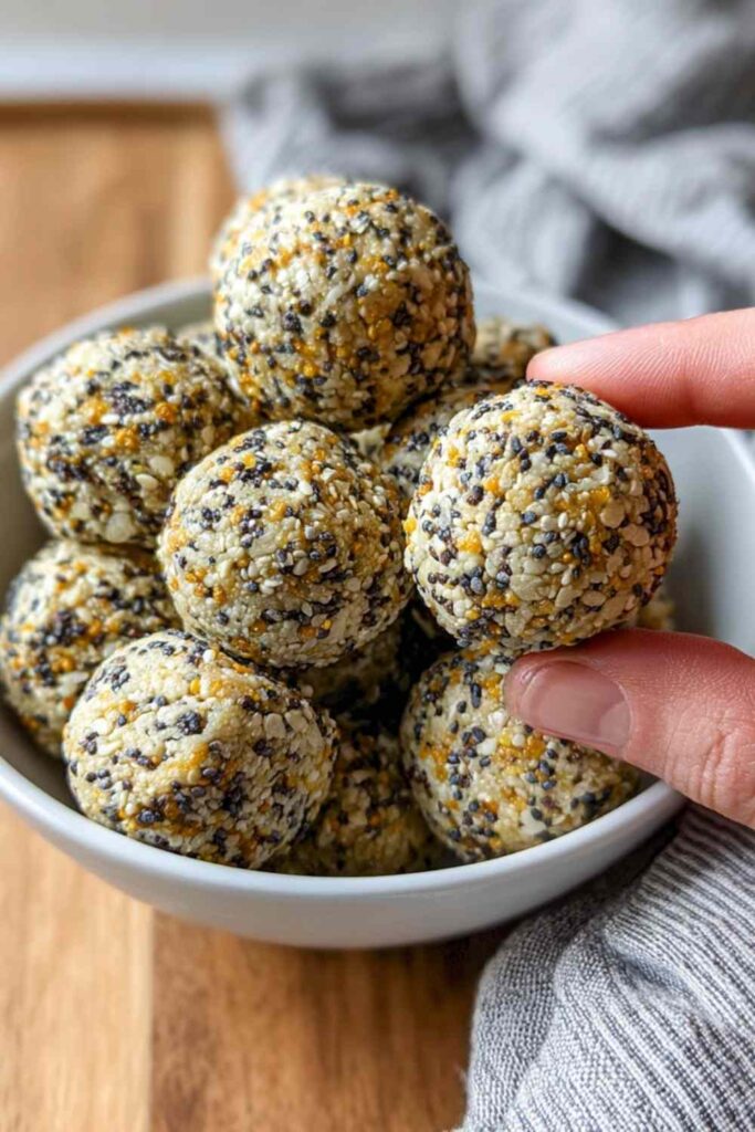 A hand holding a finished everything bagel bite showing a close-up of the crispy texture and seasoning