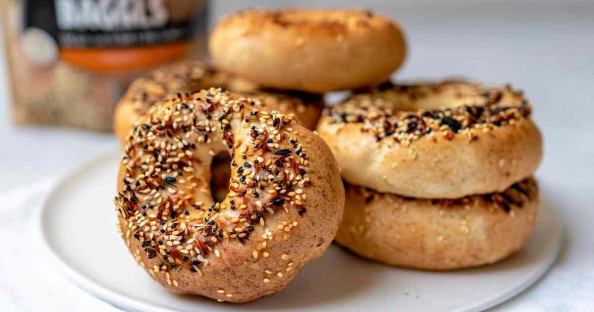 Stack of Thomas' high protein bagels topped with everything seasoning on a white plate, showcasing their golden crust and chewy texture