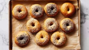 Top-down view of fresh baked bagels on parchment paper with scattered seeds