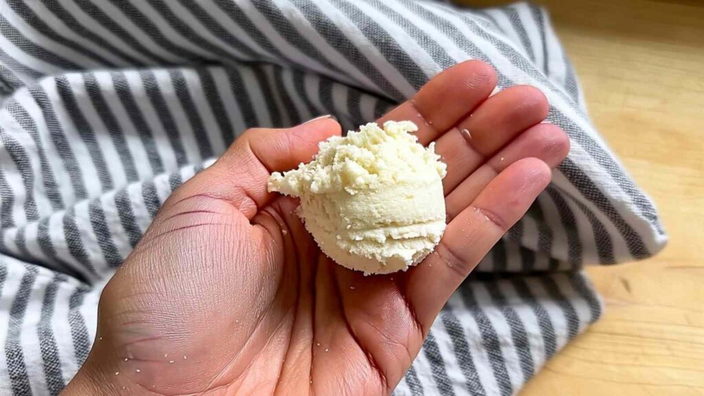 A hand holding a perfectly scooped ball of keto dough