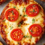 Close-up of a Margherita-style pizza bagel with melted cheese, sliced cherry tomatoes, and chopped fresh basil