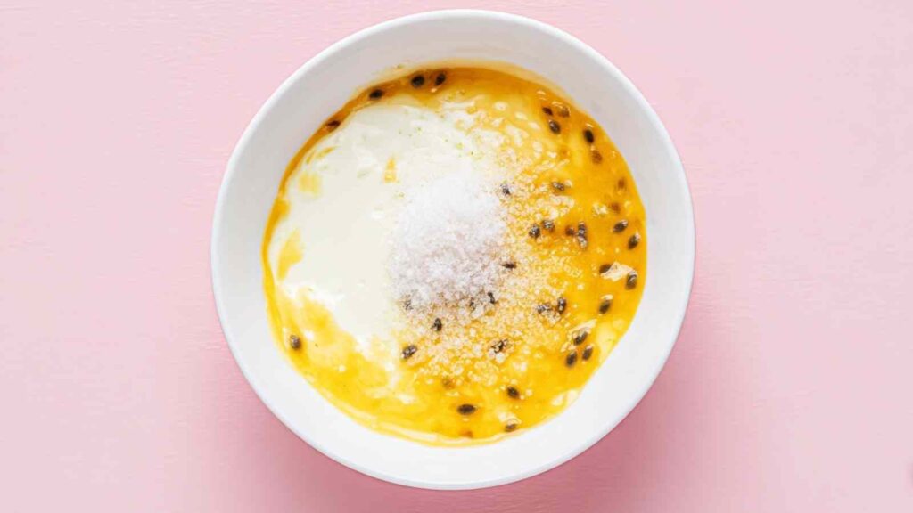 White bowl with passion fruit pulp, powdered sugar, and cream cheese.