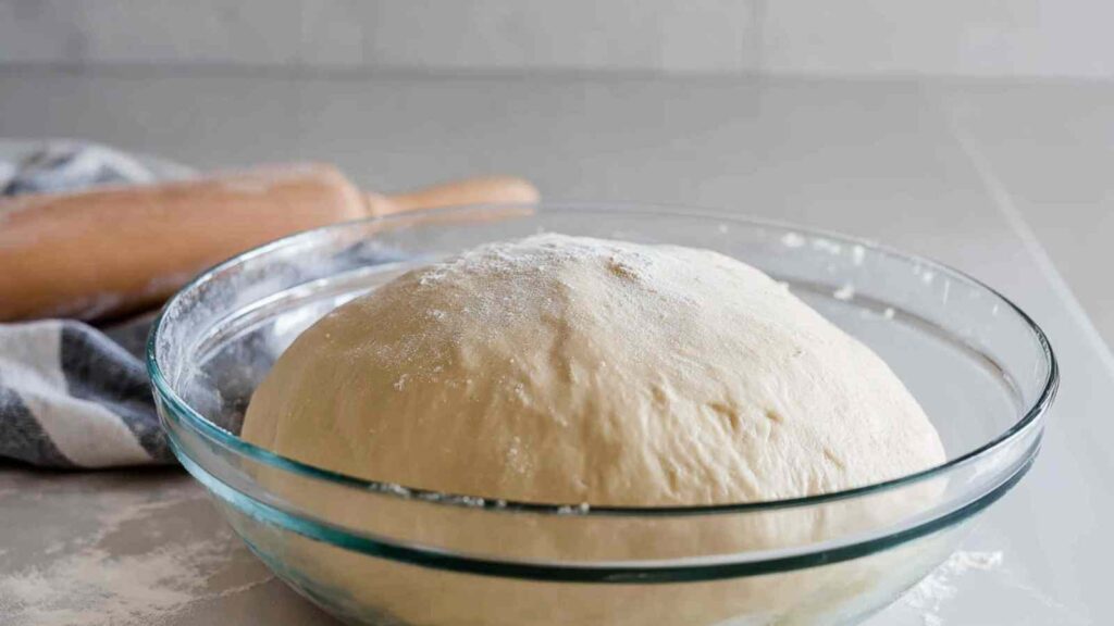 Glass bowl filled with risen dough, ready to be shaped into bagels