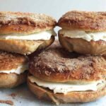Stack of cinnamon sugar bagels filled with cream cheese on a baking tray, showing their crunchy cinnamon topping.