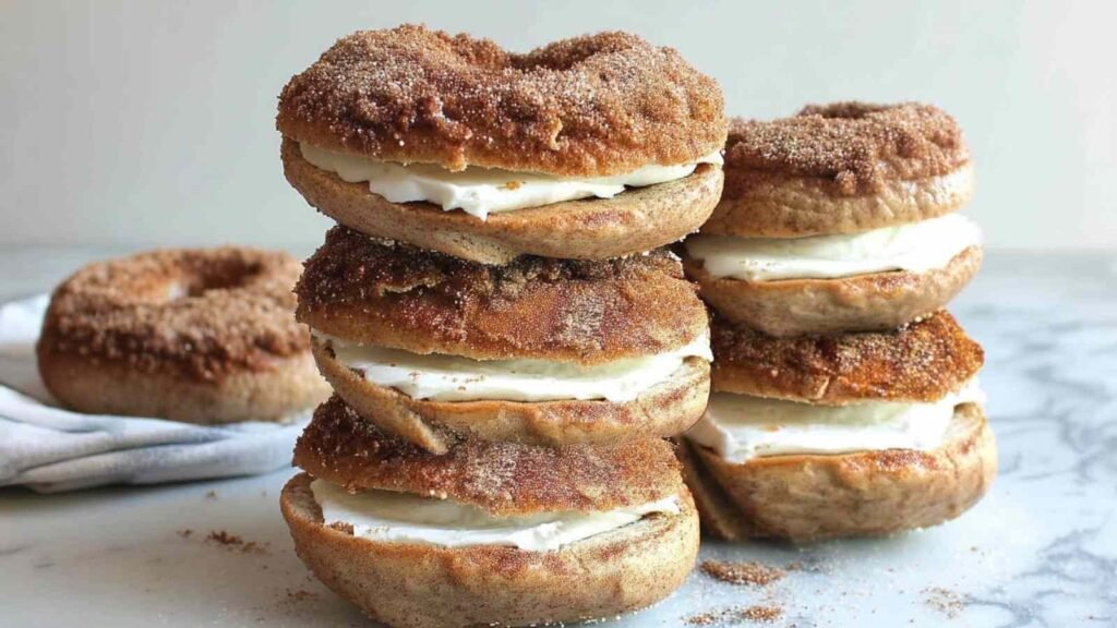 Three stacked cinnamon sugar bagels with visible cream cheese filling and a sugary cinnamon coating.