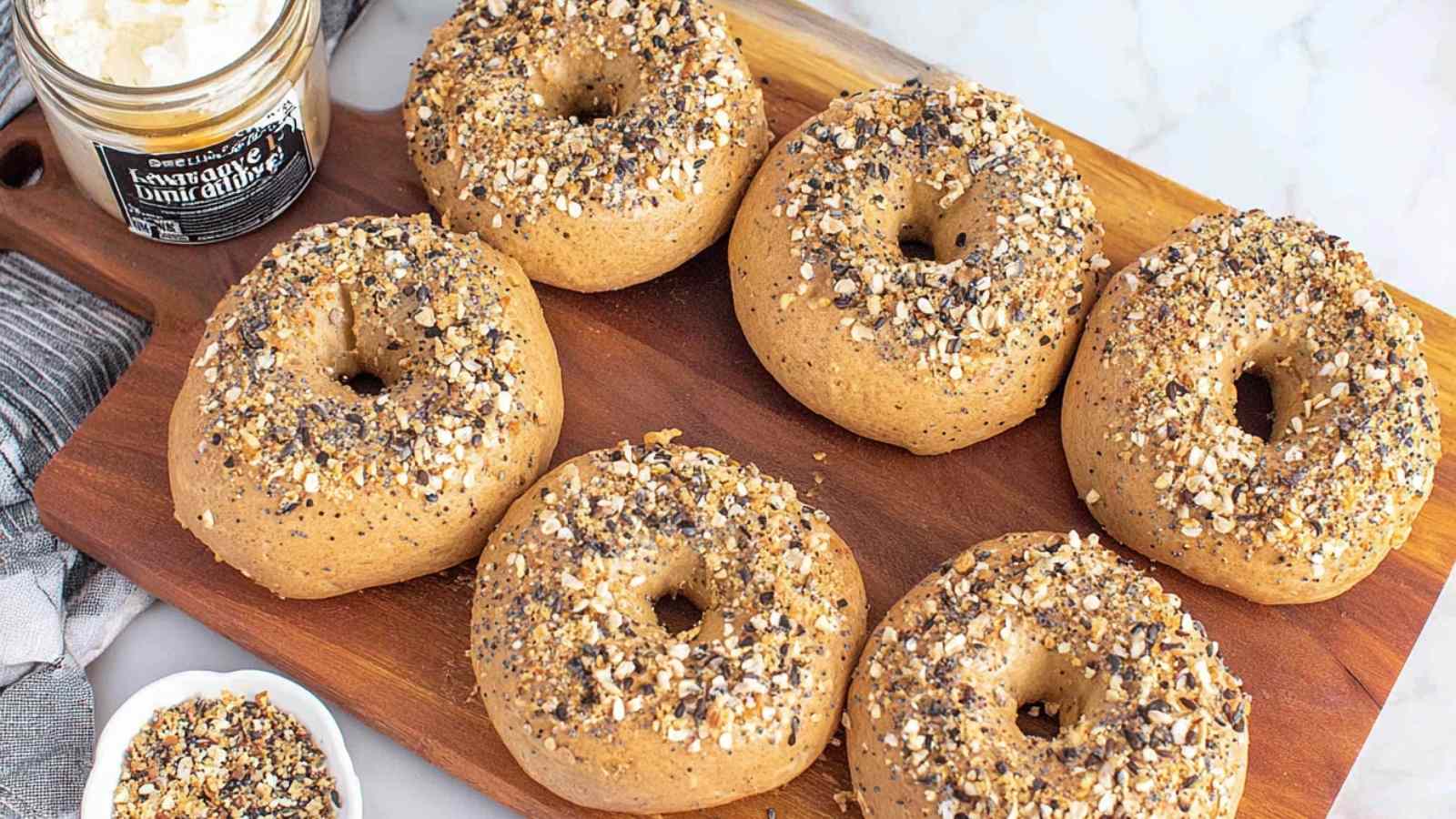 Close-up of freshly baked whole wheat bagels topped with Everything seasoning on a wooden cutting board