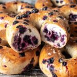 Blueberry bagel cut open on a wire rack, showing juicy berries and fluffy texture inside.