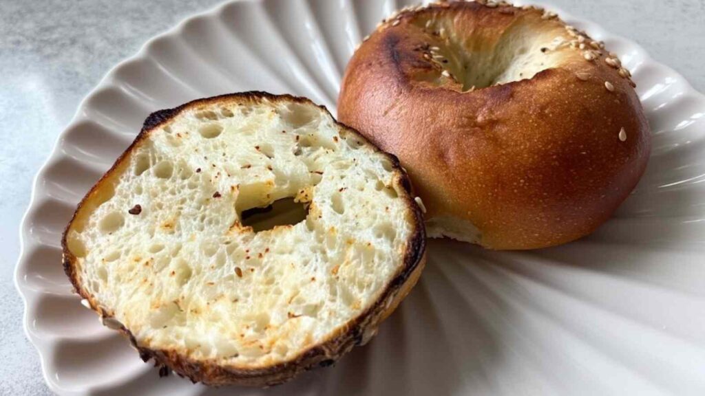 Sliced Greek yogurt bagel on a plate, showing the airy interior and lightly toasted edge.