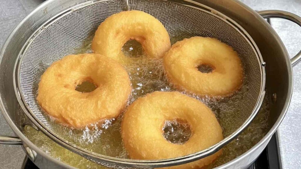 Sourdough pumpkin bagels being boiled in a pot of water to achieve their chewy texture