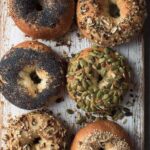 Six golden brown bagels topped with seeds like sesame, poppy, and pumpkin, made using Paul Hollywood’s bagel recipe