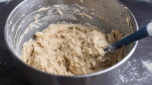Shaggy sourdough cinnamon roll dough in a metal mixing bowl