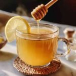 Glass of natural zepbound drink with honey drizzle and lemon wedge on rim