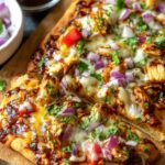BBQ chicken flatbread with melted cheese and vegetables on baking sheet