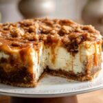 Apple crumble cheesecake slice showing layers of graham crust, creamy filling, apple pieces, and golden crumble topping