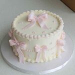 Classic ribbon bow birthday cake with pink buttercream rosettes and satin ribbon decorations