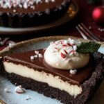 Dark chocolate peppermint mousse tart with glossy chocolate glaze on white plate