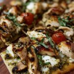 Pesto chicken flatbread with melted cheese and cherry tomatoes on baking sheet