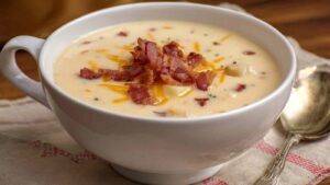 Wisconsin bacon and potato cheese soup in white bowl with bacon garnish