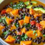 Black bean sweet potato soup in white bowl topped with cilantro and tortilla chips