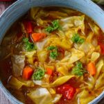 Large pot of cabbage soup diet with wooden spoon showing hearty vegetables