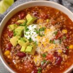 Easy taco soup recipe in white bowl topped with cheese, sour cream, and avocado
