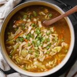 Bowl of paleo egg roll soup with ground pork, cabbage, carrots and green onions garnish
