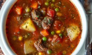 Vegetable beef soup in white bowl with tender beef chunks and colorful vegetables in rich broth